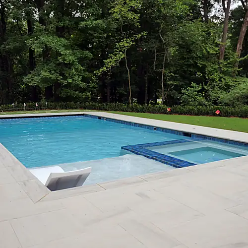 Finished pool and limestone deck beside the wooded property edge