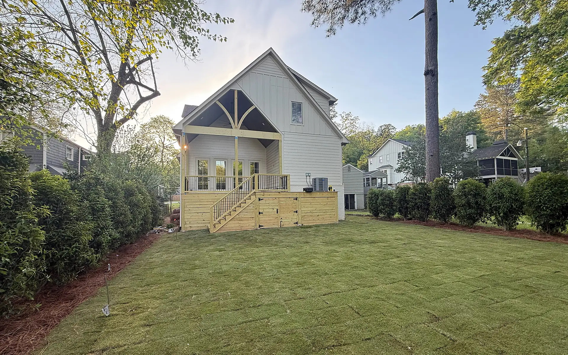 Completed backyard landscape installation with new sod, privacy planting, and mulched bed edges
