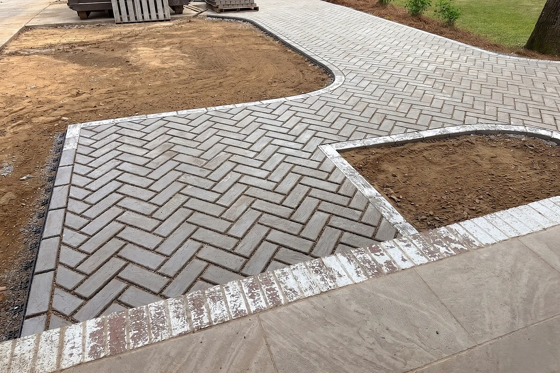 Finished paver walk showing curved geometry and herringbone layout
